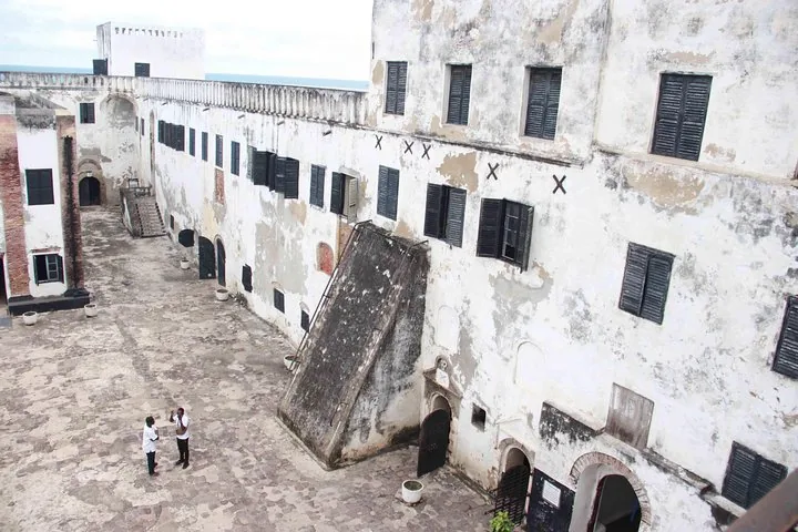 Deux personnes debout dans la grande cour d'un bâtiment historique blanc avec de nombreuses fenêtres.